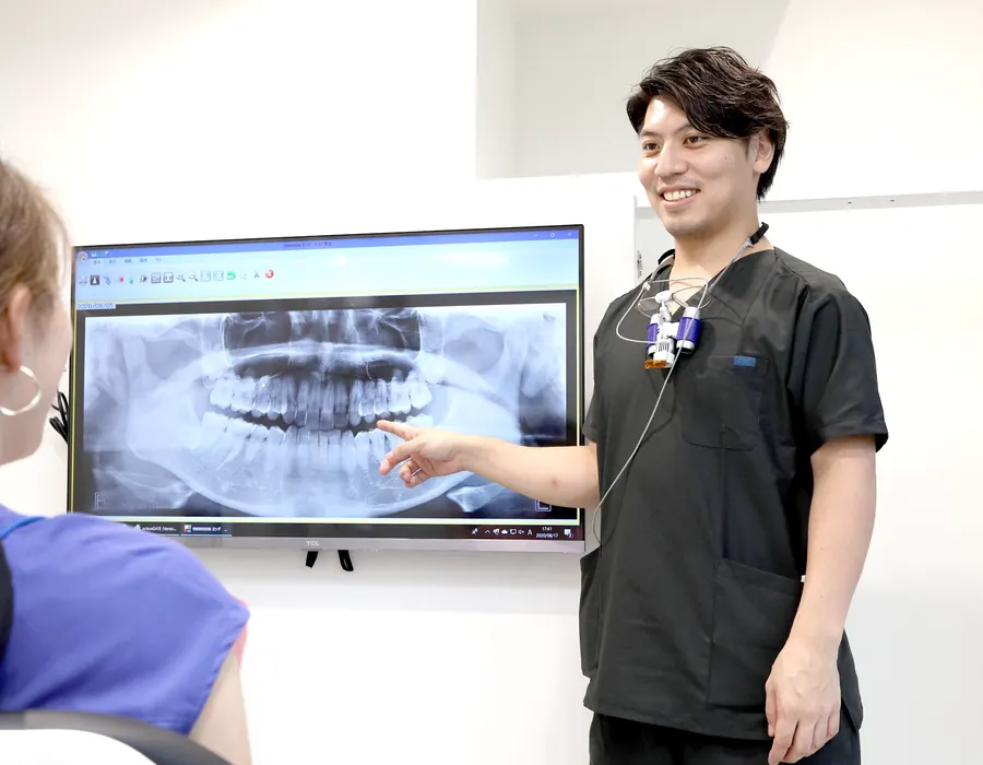 レントゲン画像を見ながら治療内容を説明する歯科医師